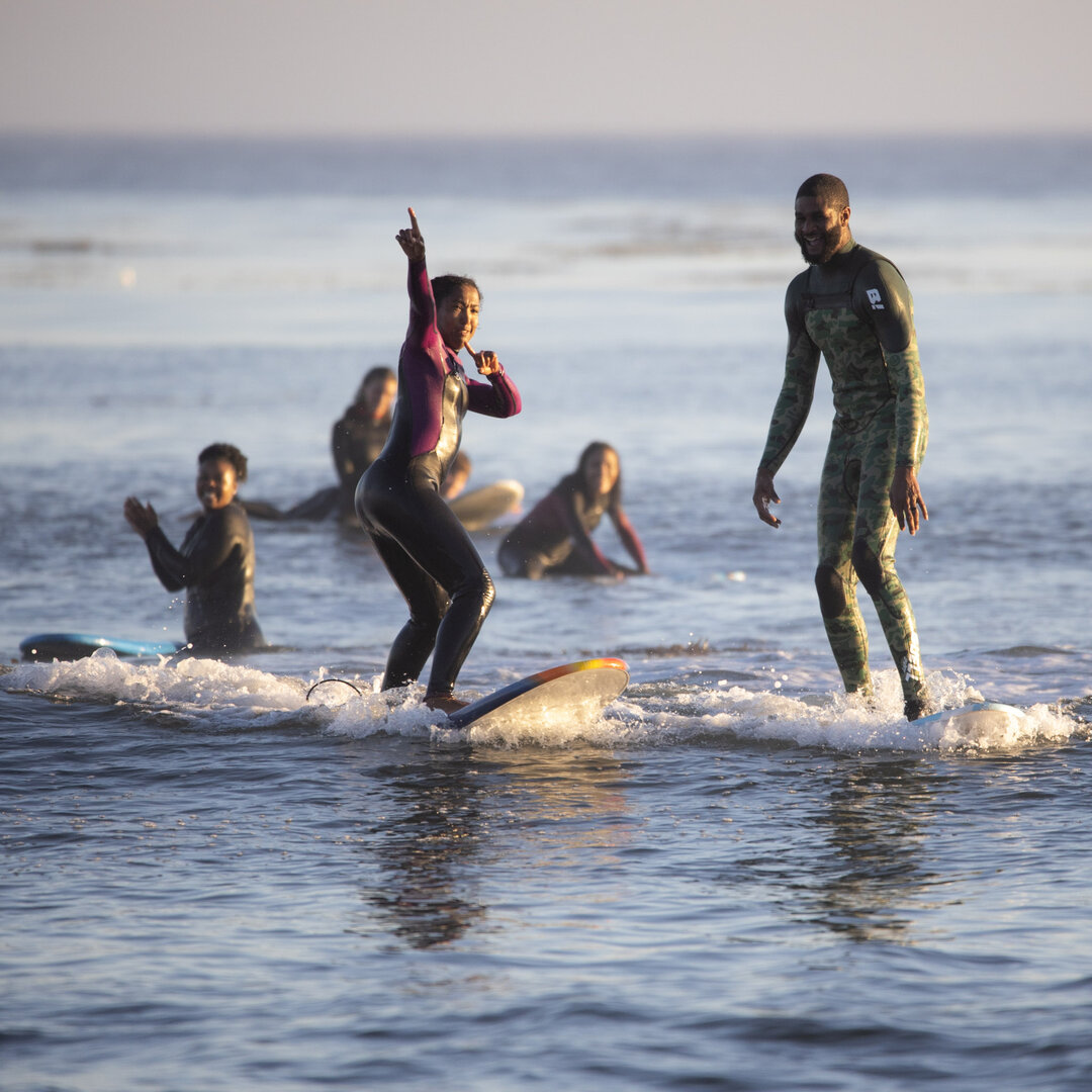 Black surfers riding on their surfboards