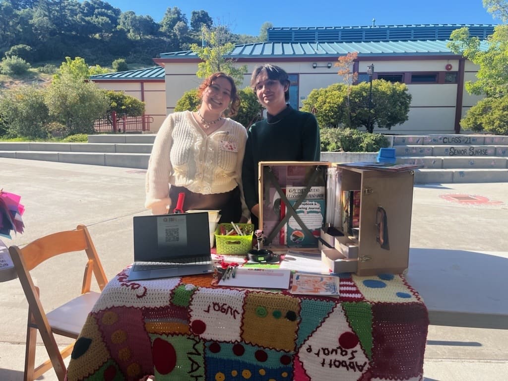 Two students standing behind a stand